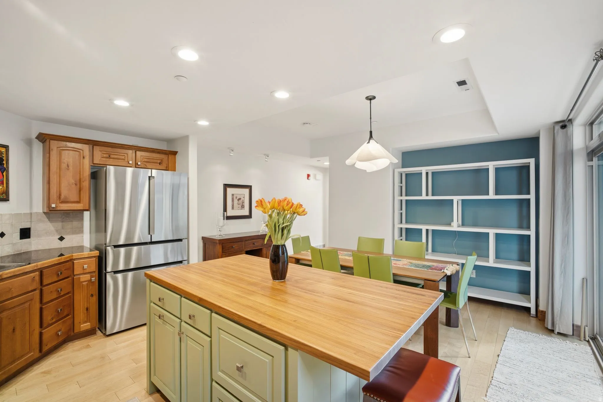 Kitchen featuring a central island with wood countertop, light green base cabinetry, and integrated seating
