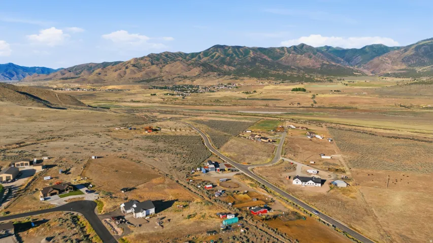 Expansive rural landscape featuring a mountainous backdrop and scattered residential properties
