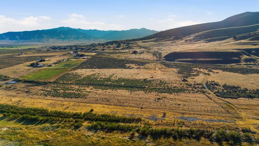 Expansive land featuring a mix of cultivated fields and natural terrain with distant mountain ranges