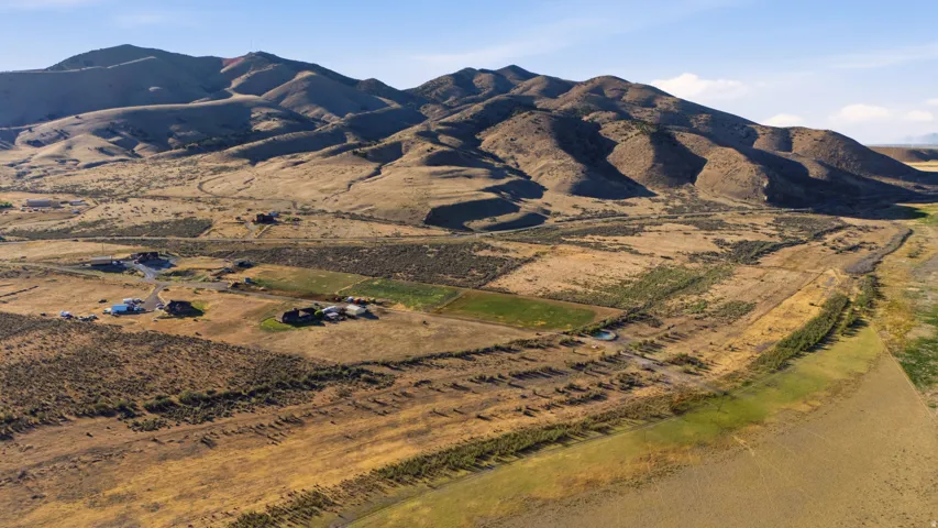 Expansive rural property featuring multiple structures set against a mountainous backdrop