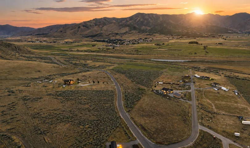 Expansive undeveloped land with distant mountain ranges and scattered residential structures