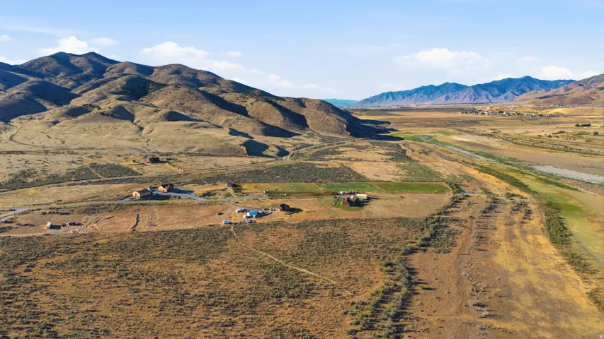 Expansive rural property featuring multiple structures, surrounded by rolling hills and distant mountains