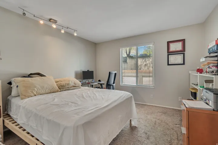 Carpeted room featuring a window with horizontal blinds, track lighting, and neutral wall tones