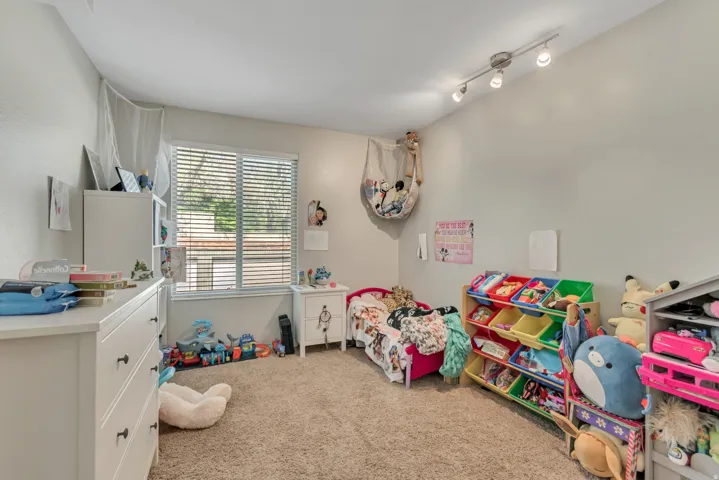 Carpeted room featuring a single window with blinds, light gray walls, and track lighting