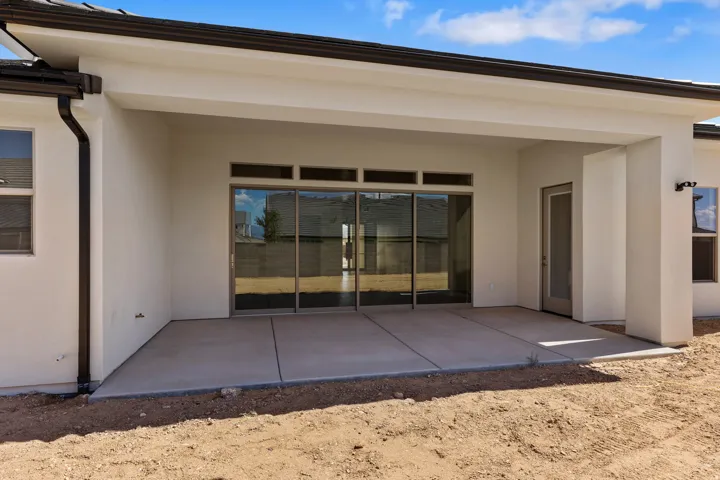 Covered concrete patio with sliding glass doors and transom windows
