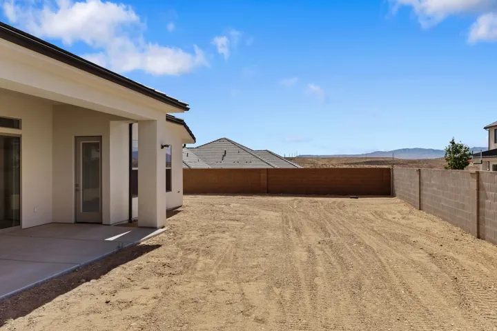Expansive outdoor space featuring a paved patio, a large open yard, and block wall fencing