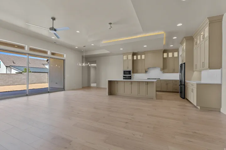 Open-concept living space featuring wood-finish flooring, a modern kitchen with light-toned cabinetry, a spacious island with a light-toned countertop, and recessed lighting