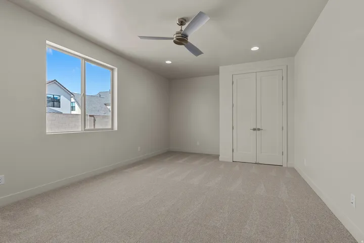 Spacious room featuring neutral carpeting, a large window, a modern ceiling fan, recessed lighting, and double-door entry