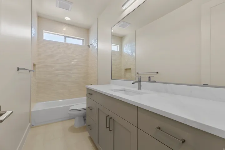 Bathroom featuring a full-length vanity mirror, a single basin sink, and a spacious vanity with integrated storage