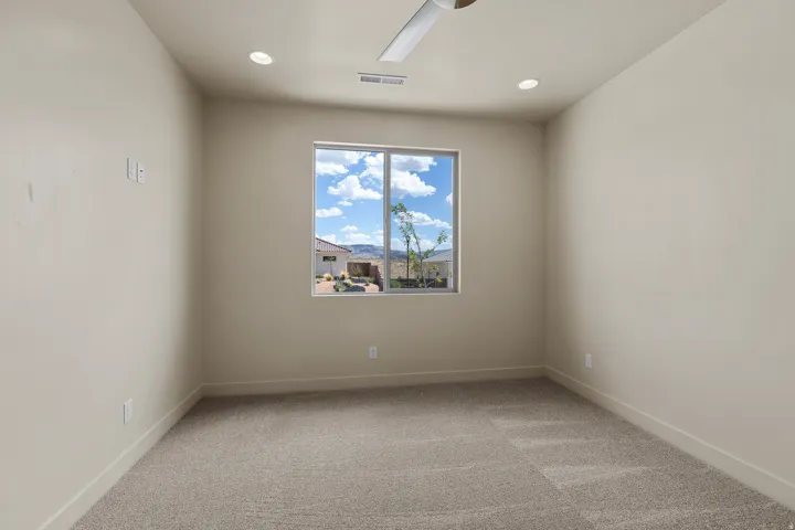 Carpeted interior room featuring a large window, recessed lighting, and a ceiling fan