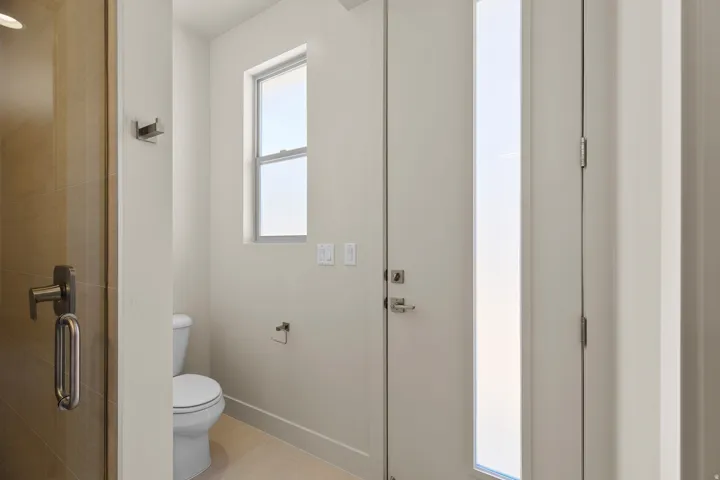 Powder room featuring a white toilet, light-toned floor tiling, and a rectangular window