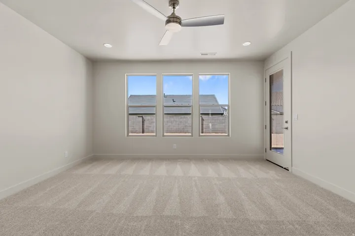 Spacious room featuring neutral carpeting, three large windows, a glass-paneled exterior door, a ceiling fan, and recessed lighting