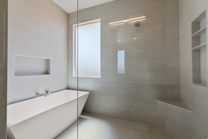Freestanding soaking tub with a wall-mounted faucet, complemented by a tiled accent wall with an integrated niche