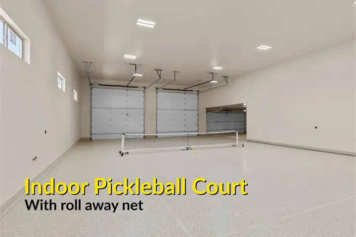 Spacious multi-purpose room featuring a light-colored epoxy floor, multiple overhead garage doors, recessed ceiling lighting, and high-set windows