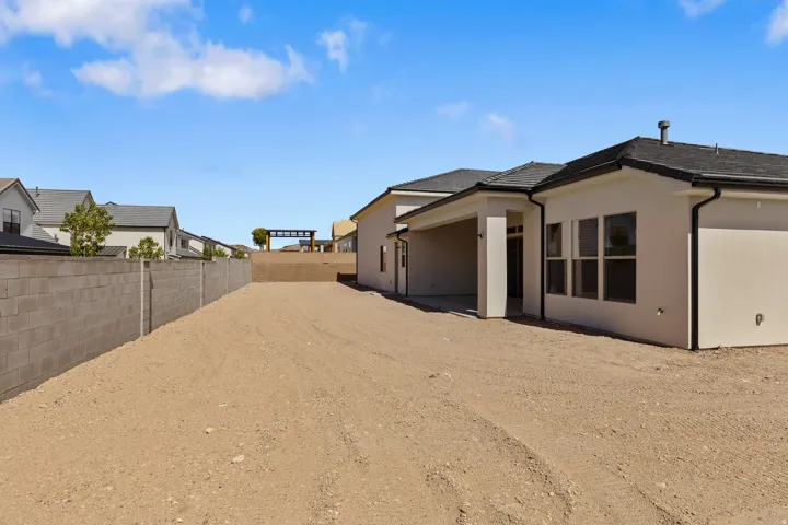 Spacious rear yard with a concrete block privacy wall and a covered patio area
