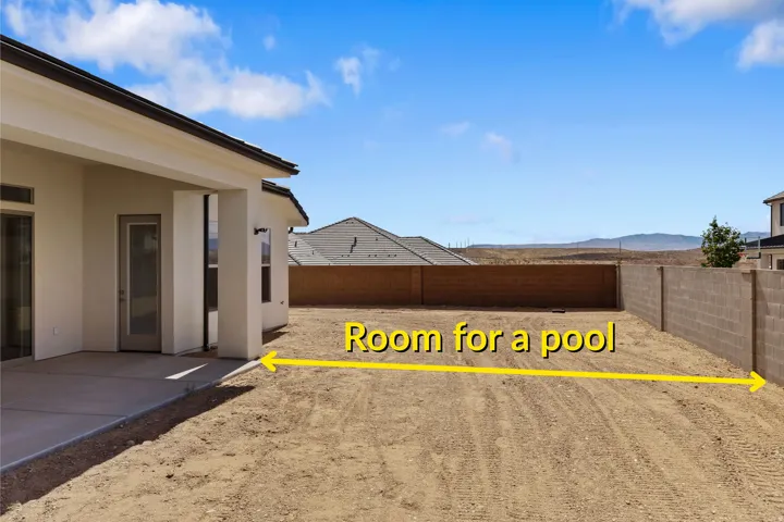 Expansive rear yard featuring an attached covered patio, concrete block perimeter fencing, and a vast undeveloped space