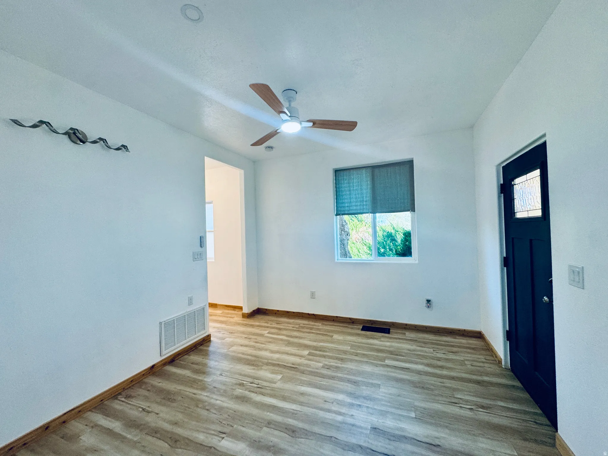 Bright room featuring wood-finish flooring and a contemporary ceiling fan