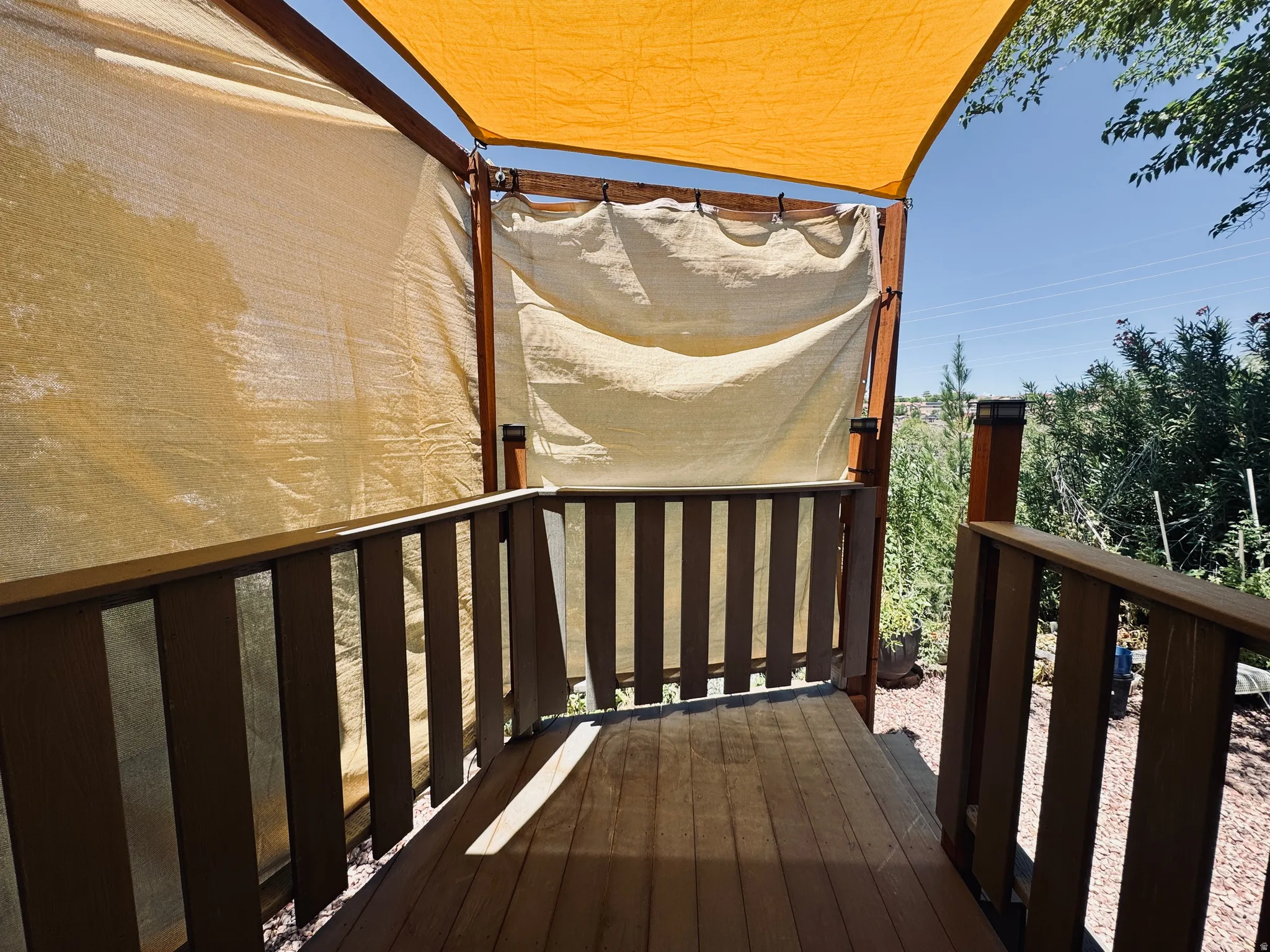 Wood-finish decking with coordinating railings, shaded by a light-colored fabric canopy and side panels