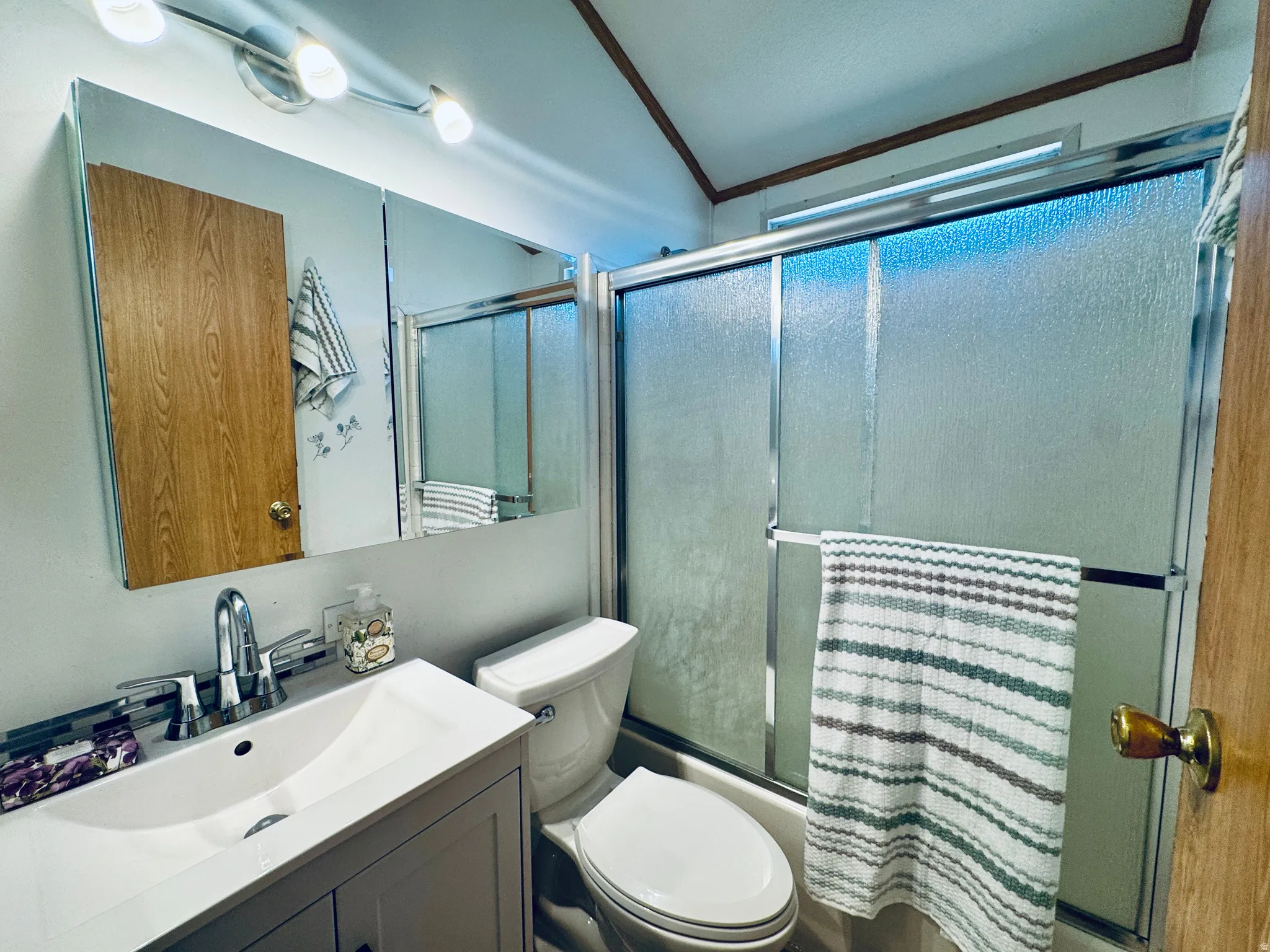 Bathroom featuring a white vanity with integrated sink, chrome faucet, and a wall-mounted mirrored medicine cabinet