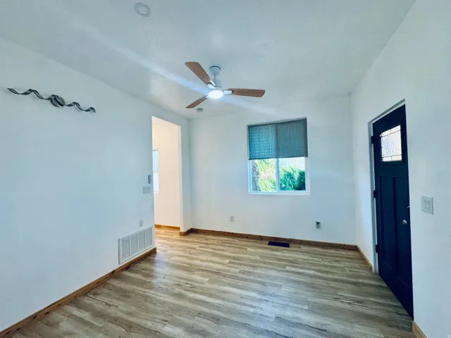 Bright room featuring wood-finish flooring and a contemporary ceiling fan
