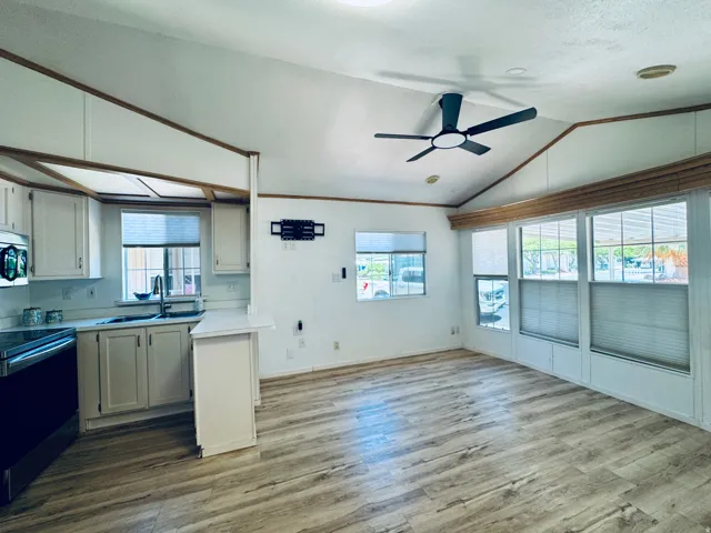 Open-concept living space featuring wood-finish flooring, vaulted ceilings, and a contemporary ceiling fan