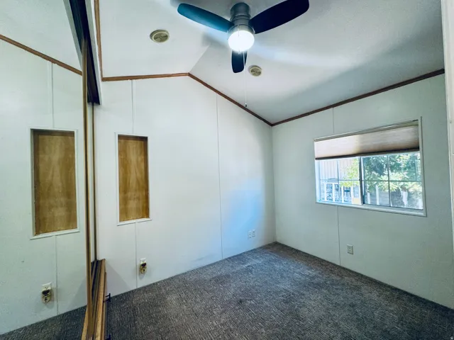Interior room featuring a vaulted ceiling, ceiling fan, and carpet flooring