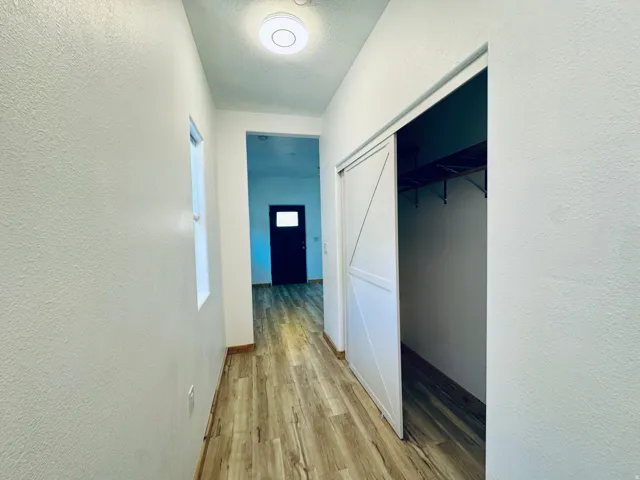 Hallway featuring wood-finish flooring, white walls, and a window providing natural light