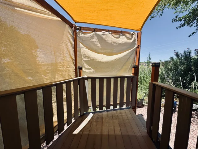 Wood-finish decking with coordinating railings, shaded by a light-colored fabric canopy and side panels