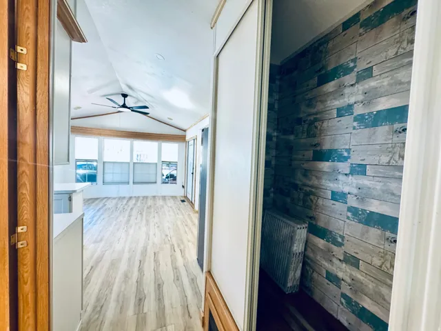 Open-concept living space featuring wood-finish flooring, a vaulted ceiling, and a contemporary ceiling fan