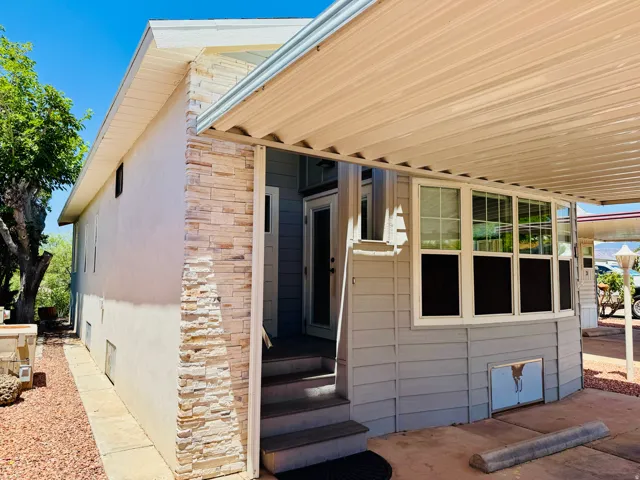 Exterior featuring light stucco siding, stacked stone accents, multiple large windows, and a covered entry