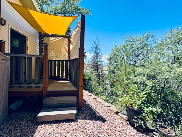 Outdoor deck featuring a wood-finish railing, steps, and a sun shade canopy