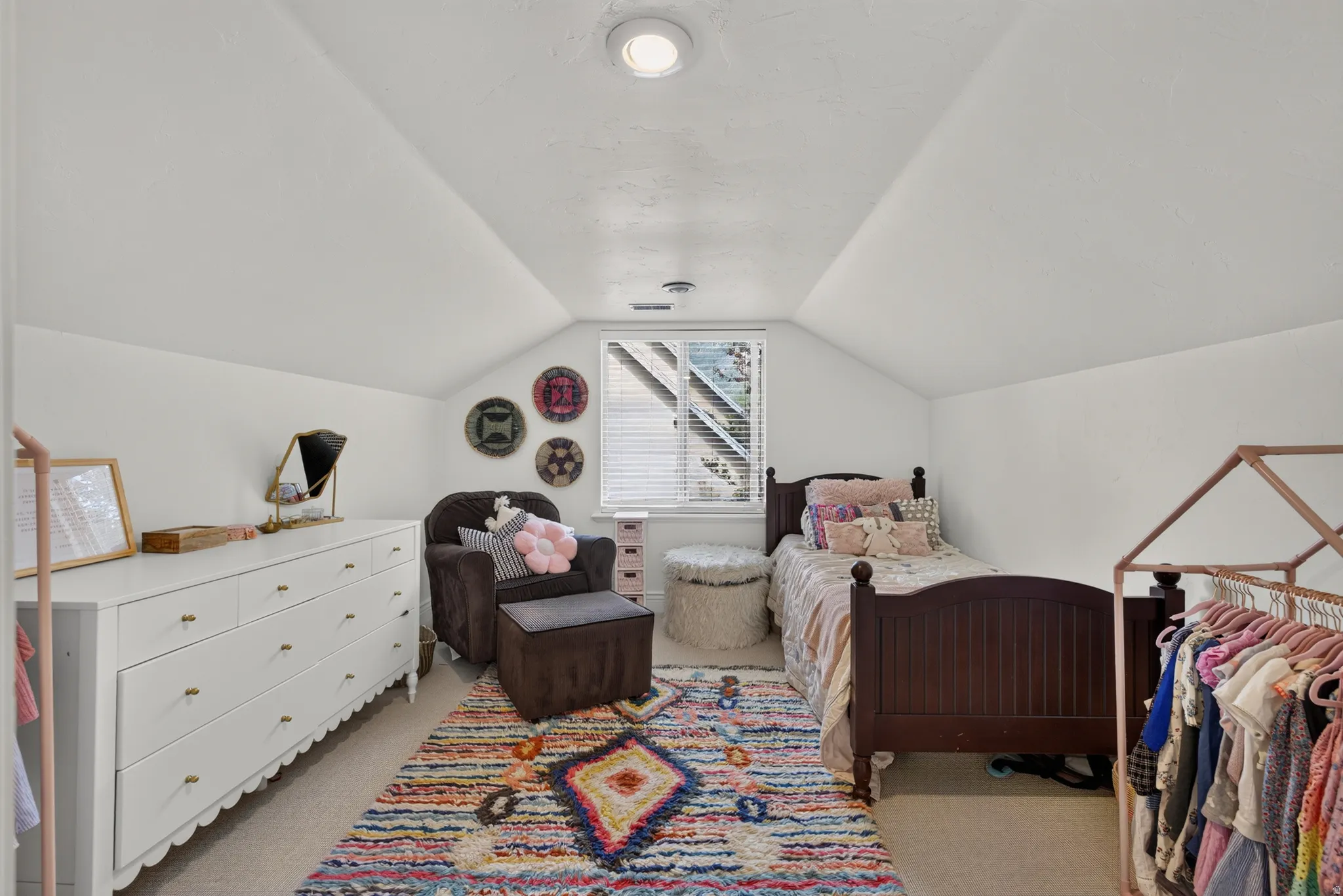 Attic room with angled ceilings, recessed lighting, and a single window offering natural illumination