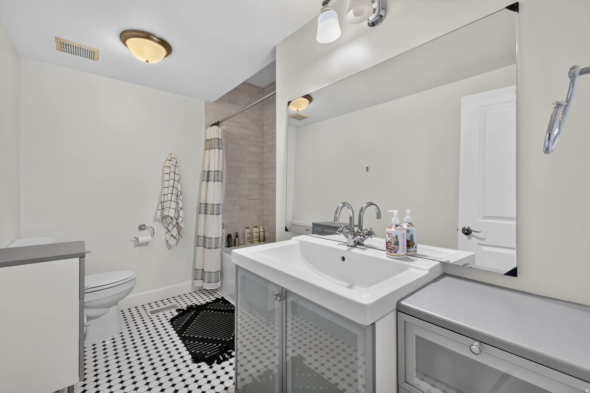 Bathroom featuring a white vanity with integrated sink, chrome fixtures, and a large wall-mounted mirror