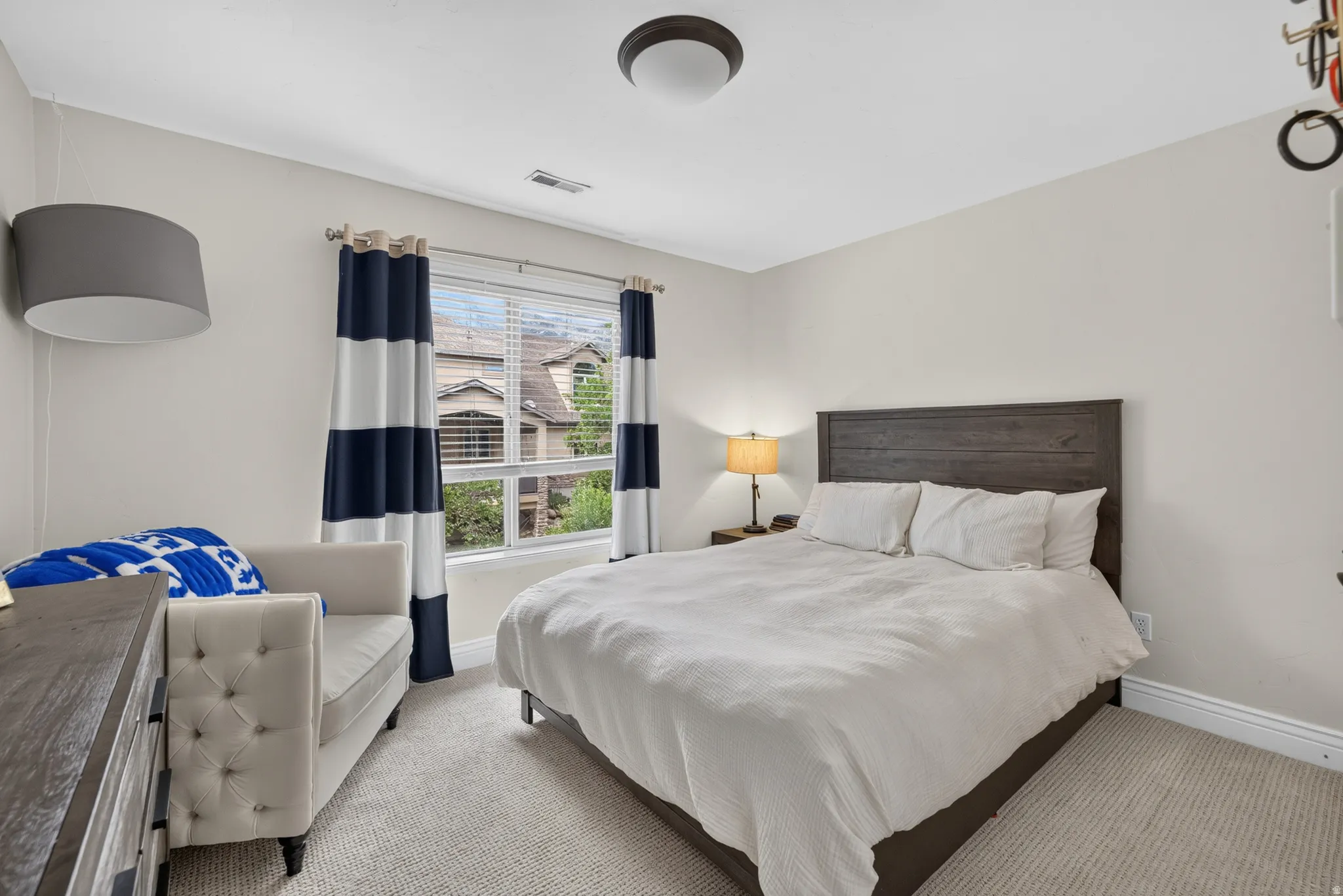 Carpeted room featuring a window with horizontal blinds, providing natural light