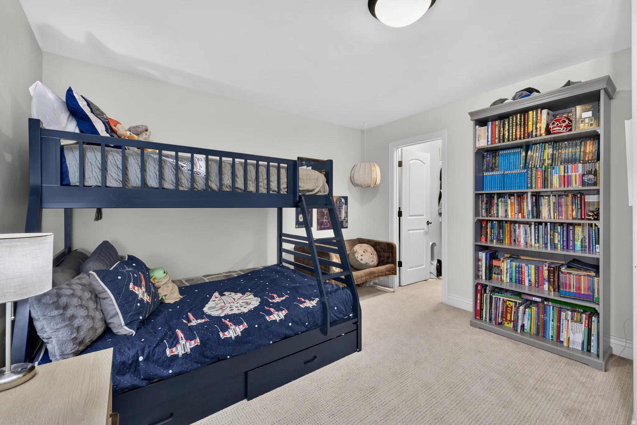 Carpeted room featuring a built-in bookshelf, a ceiling-mounted light fixture, and a white interior door