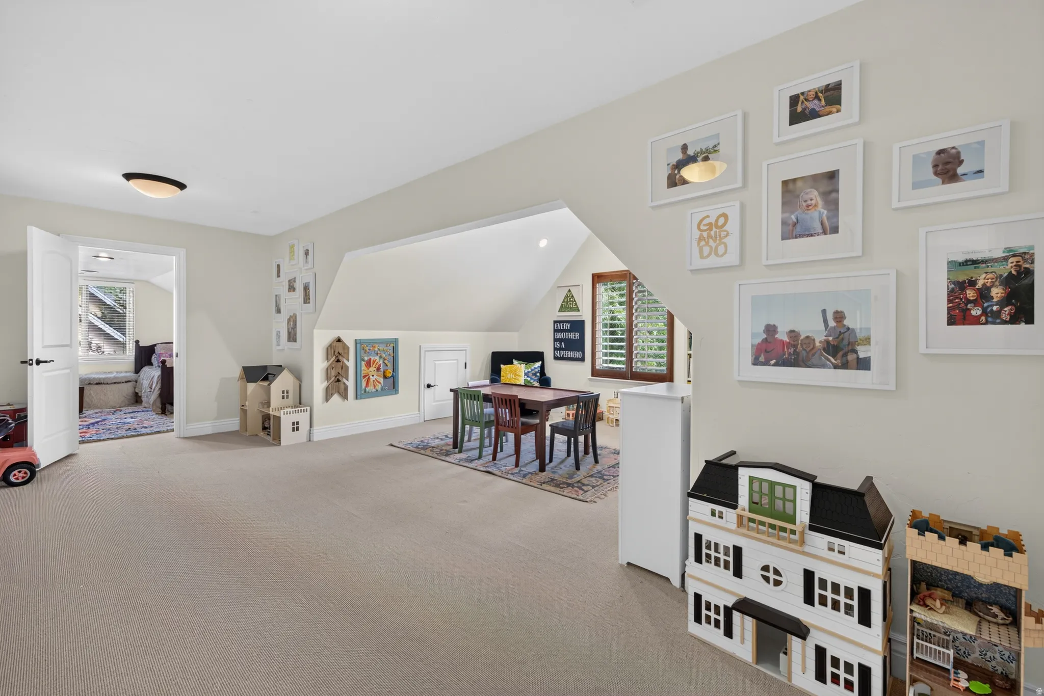 Spacious carpeted room featuring a sloped ceiling, recessed lighting, and a white paneled door