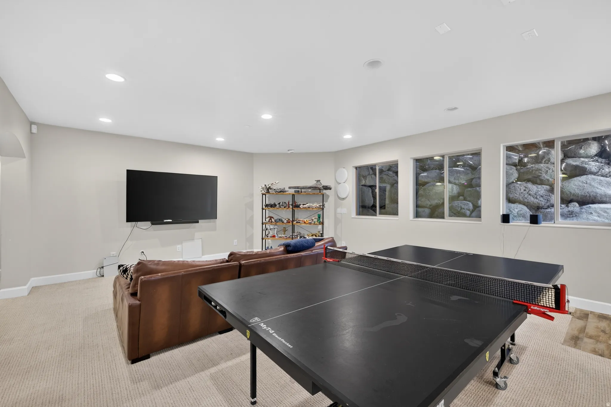 Recessed lighting illuminates this versatile space, featuring neutral carpeting and light-toned walls