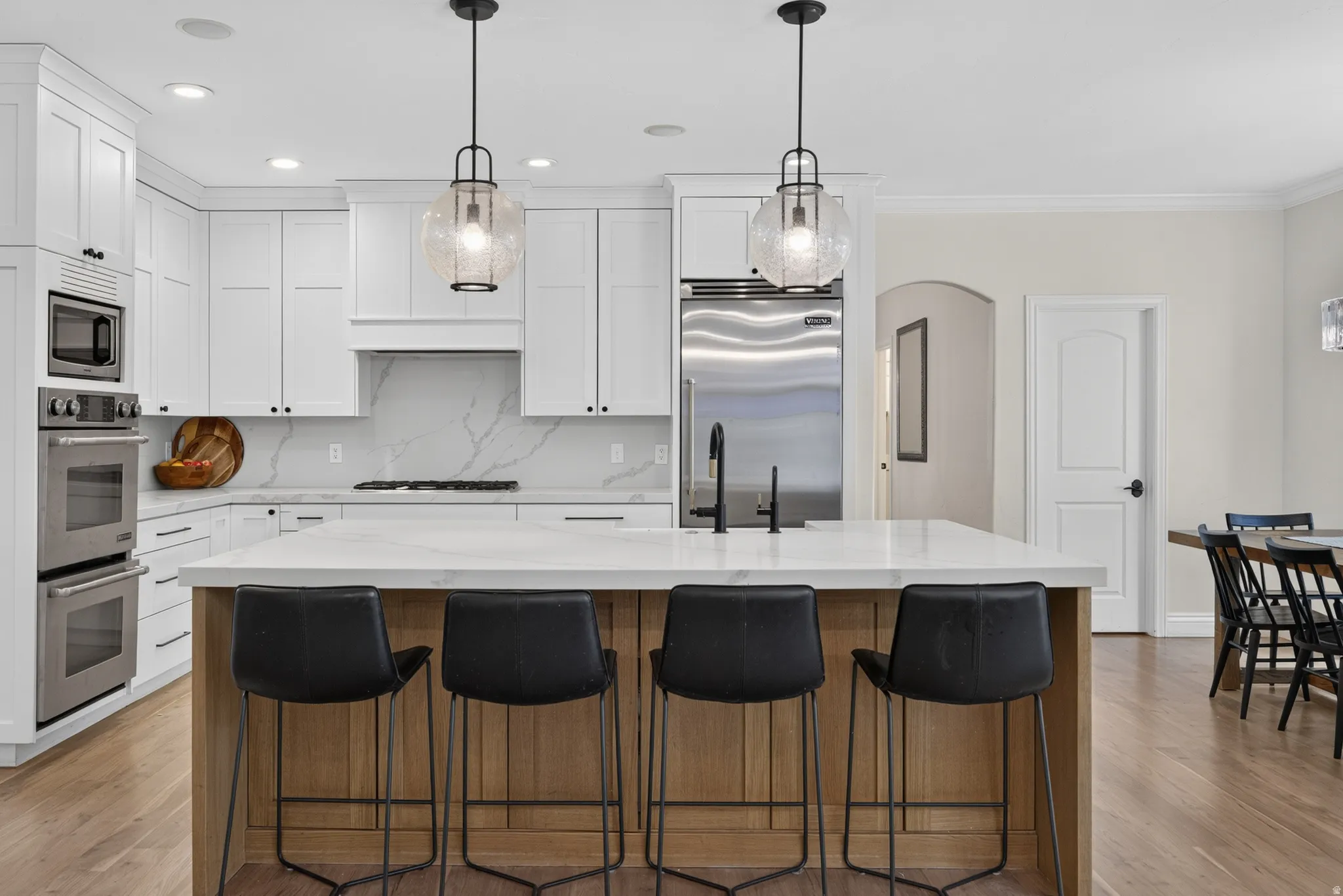 Modern kitchen with a substantial central island, white shaker cabinetry, and a full suite of stainless steel appliances