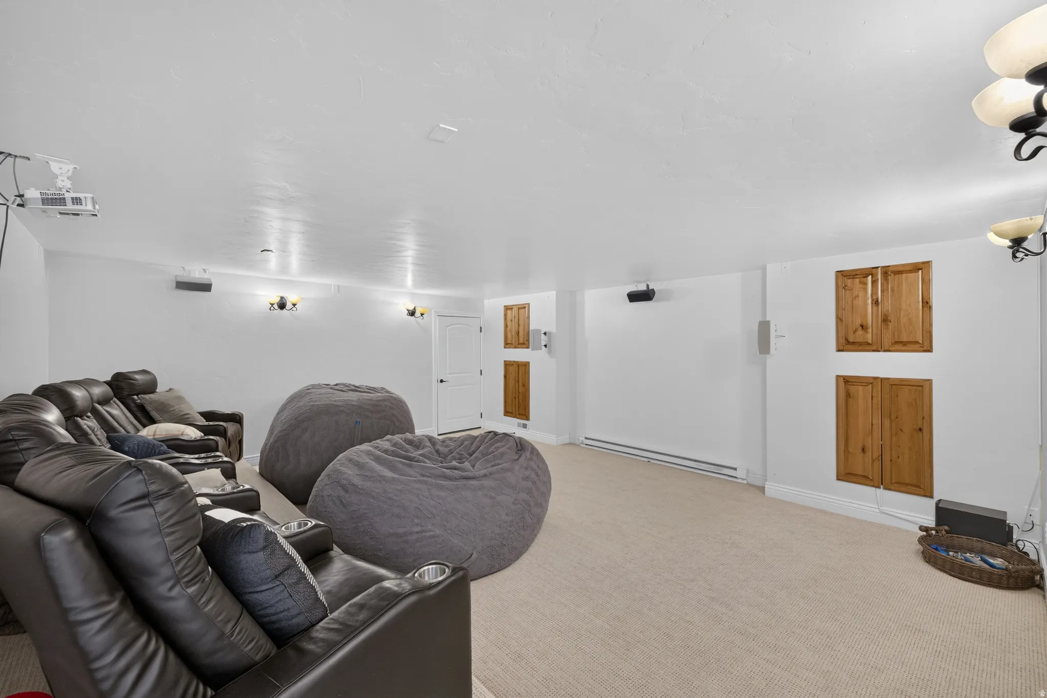 Spacious entertainment room featuring light-toned carpeting, recessed lighting, and wall-mounted sconces
