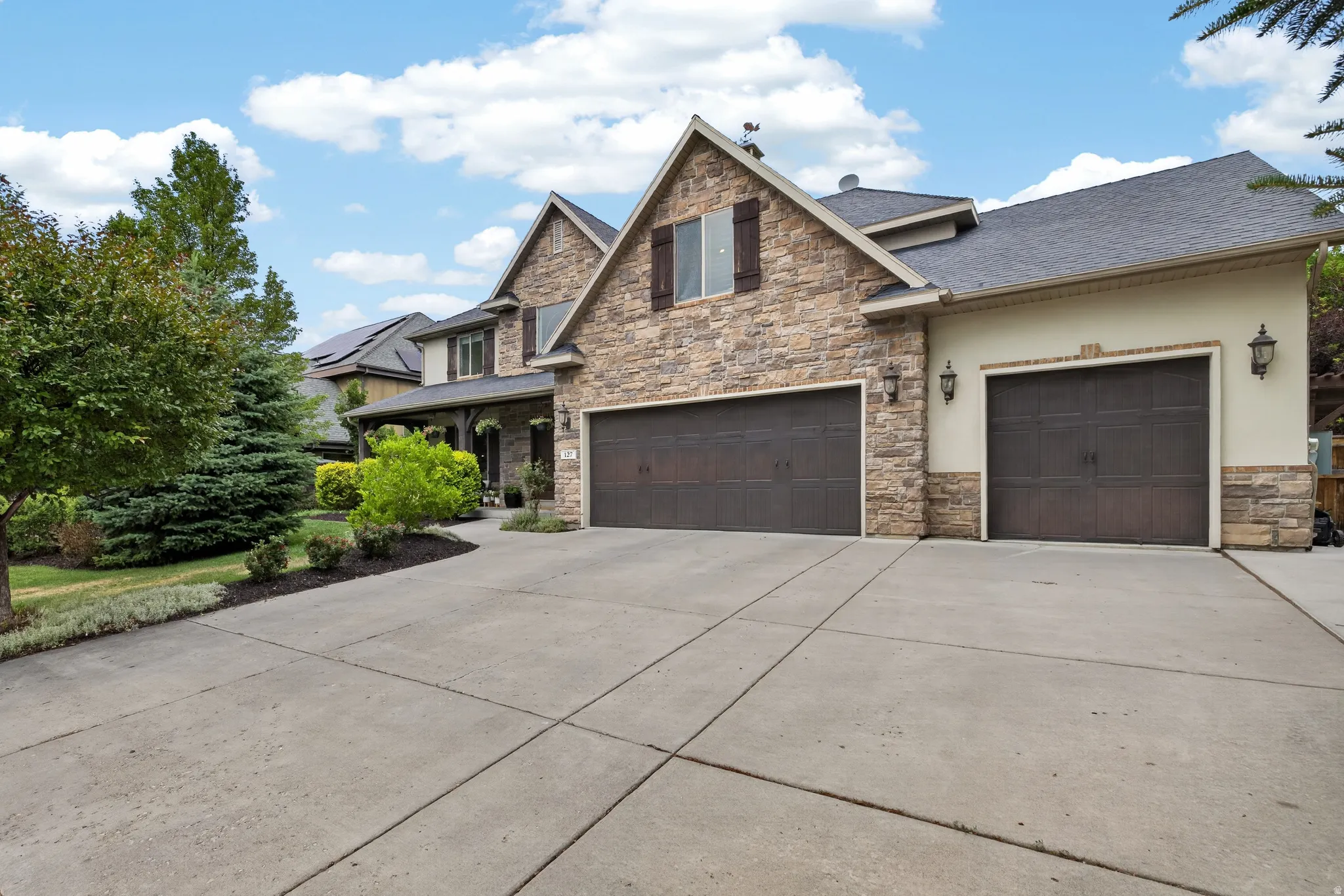 Stone and stucco exterior featuring multiple gables and dark window shutters