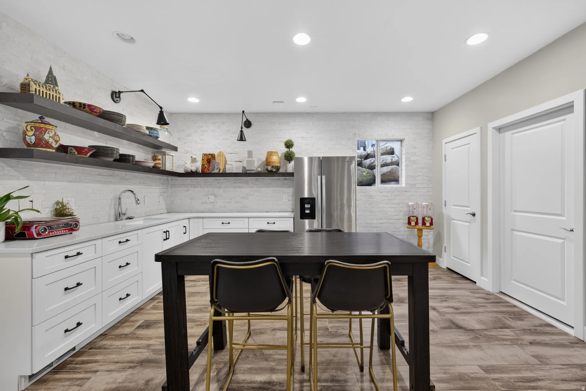 Spacious kitchen area featuring white shaker-style cabinetry, a stainless steel refrigerator, white quartz countertops, and wood-finish flooring