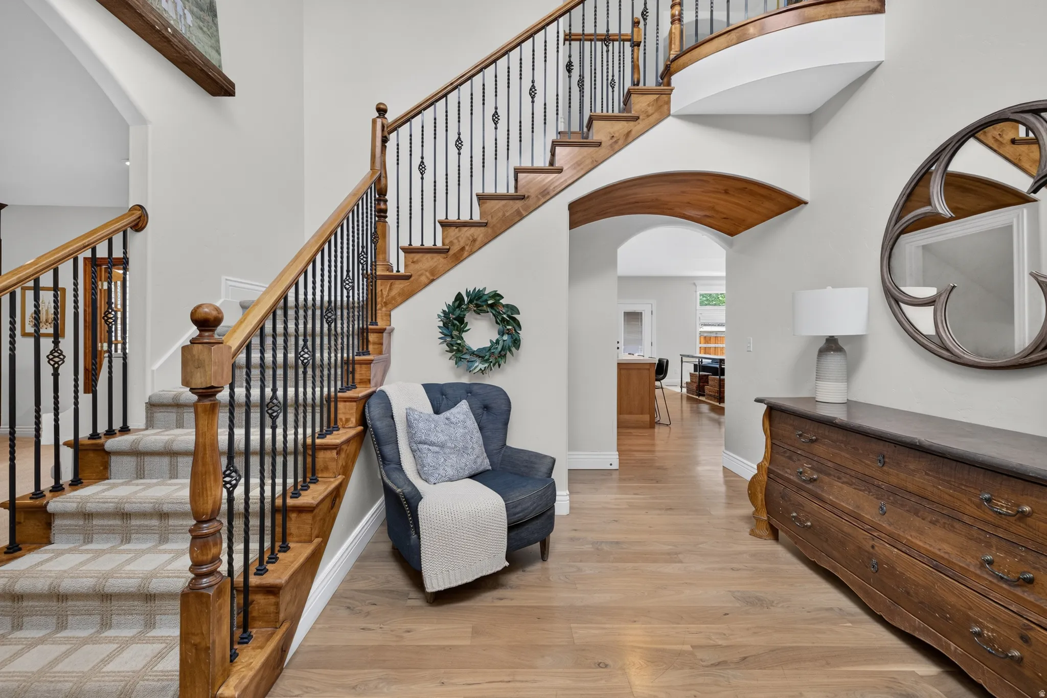 Grand staircase featuring wood treads, patterned runner, and wrought iron balusters