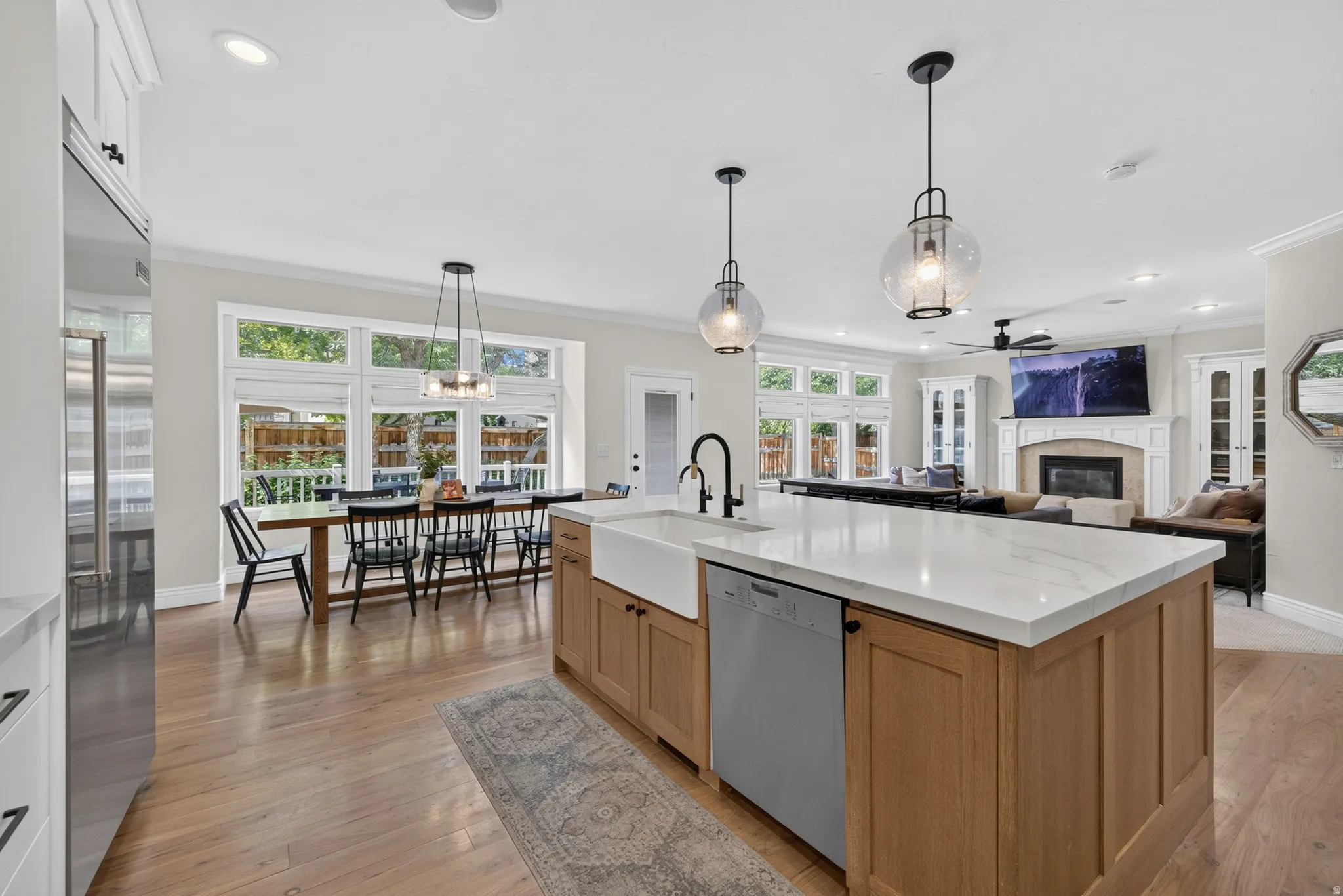 Open-concept kitchen featuring a large island with a farmhouse sink, white countertops, and wood-finish cabinetry