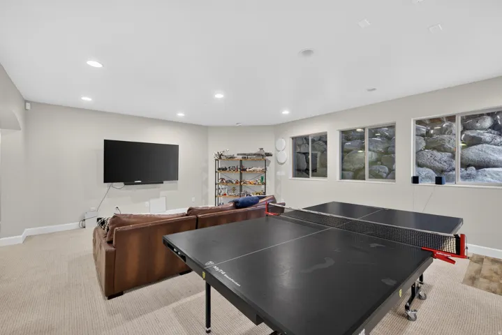 Recessed lighting illuminates this versatile space, featuring neutral carpeting and light-toned walls