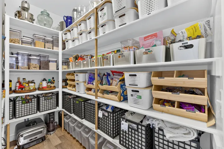 Custom pantry storage system with floor-to-ceiling shelving, wood-finish flooring, and white painted walls