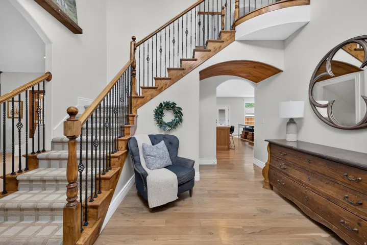 Grand staircase featuring wood treads, patterned runner, and wrought iron balusters