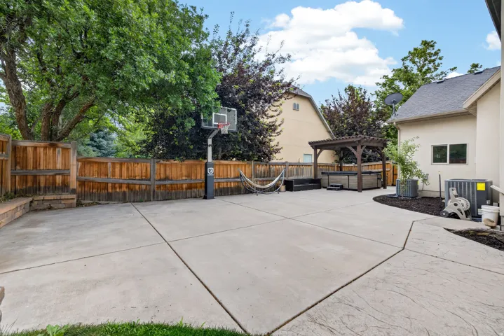 Expansive concrete patio area with a pergola-covered hot tub