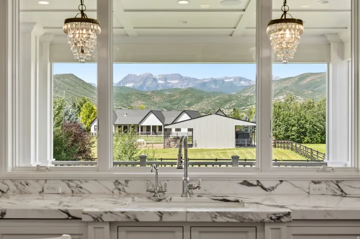 Gourmet kitchen with a large window overlooking a landscaped property, mountains, and trees