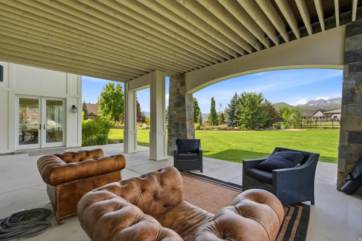Expansive covered patio featuring a concrete floor, stone-clad structural columns, and a tongue-and-groove ceiling