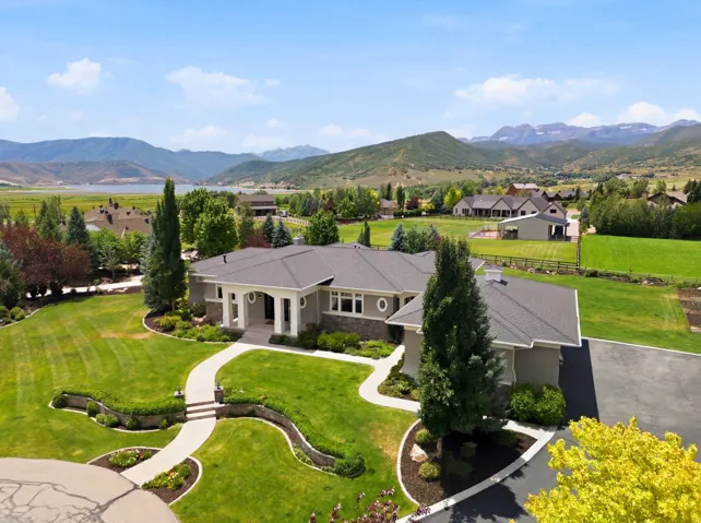 Expansive property featuring a meticulously landscaped lawn, mature trees, and a curved paved driveway